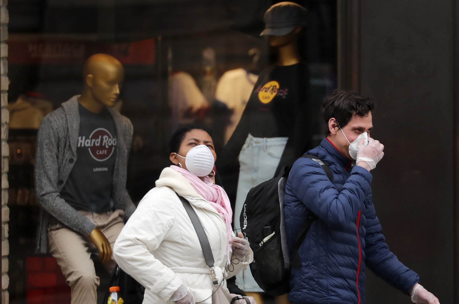 People wearing face masks walk past closed shops in London, Friday, March 20. For most people, the new coronavirus causes only mild or moderate symptoms, such as fever and cough. (AP Photo)