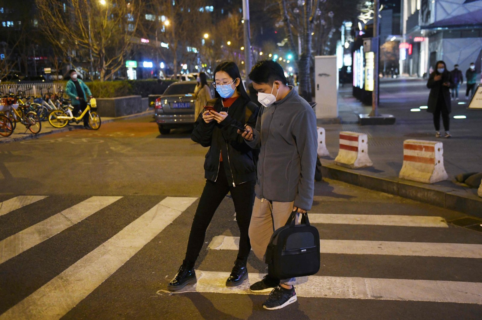 A couple, wearing masks amid concerns over the spread of the coronavirus, cross a road, Beijing. March 20, 2020. (AFP Photo)