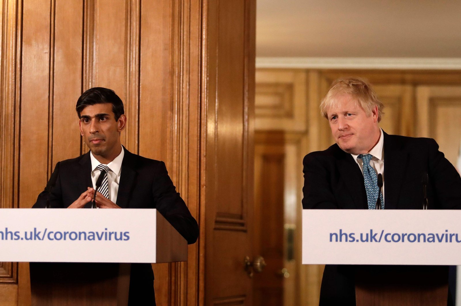 Britain's Chancellor of the Exchequer Rishi Sunak (L) and Britain's Prime Minister Boris Johnson (R) attend a news conference addressing the government's response to the novel coronavirus COVID-19 outbreak, inside 10 Downing Street in London on March 17, 2020. (AFP Photo)