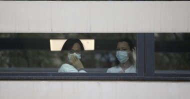 Medical staff watch people waiting in line to get a coronavirus test outside the La Timone hospital, Marseille, Monday, March 23, 2020. (AP Photo)