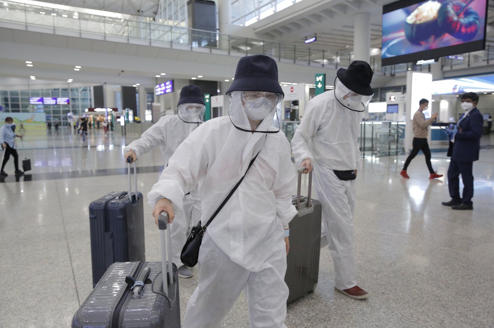 Passengers wear suits and face masks to protect against the coronavirus as they arrive at the Hong Kong airport, Monday, March 23, 2020. (AP Photo)