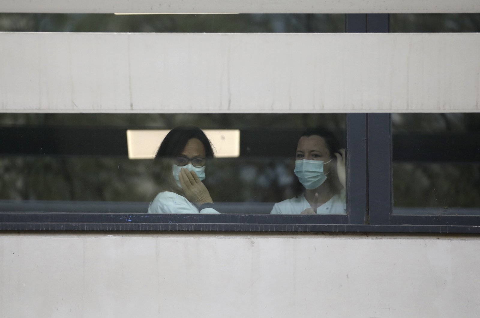 Medical staff watch people waiting in line to get a coronavirus test outside the La Timone hospital, Marseille, Monday, March 23, 2020. (AP Photo)