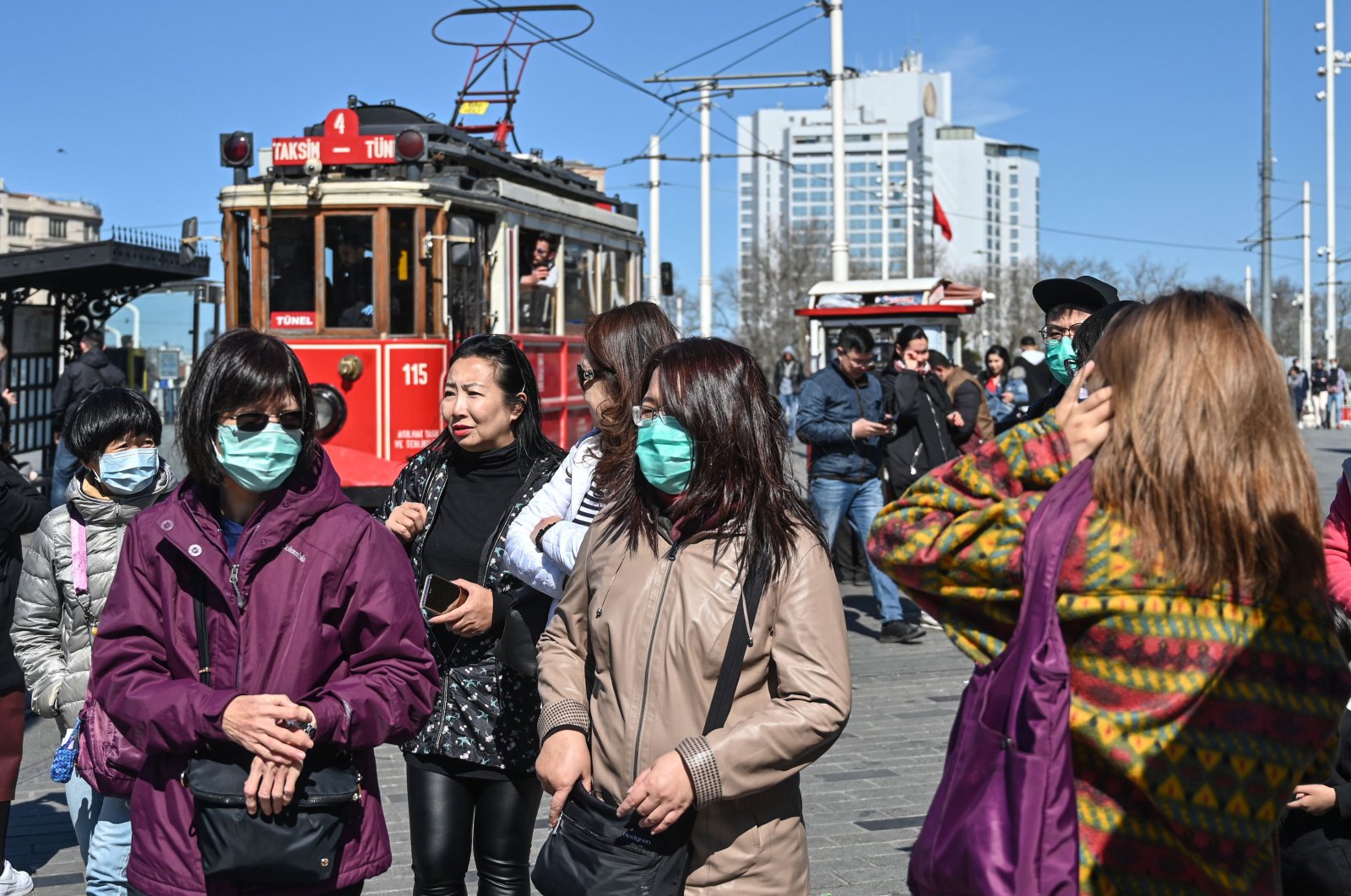 Tourists wear protective face masks as they walk at Taksim Square as the nation tries to limit the spread of the new coronavirus, in Istanbul, Tuesday, March 17, 2020. (AFP Photo)