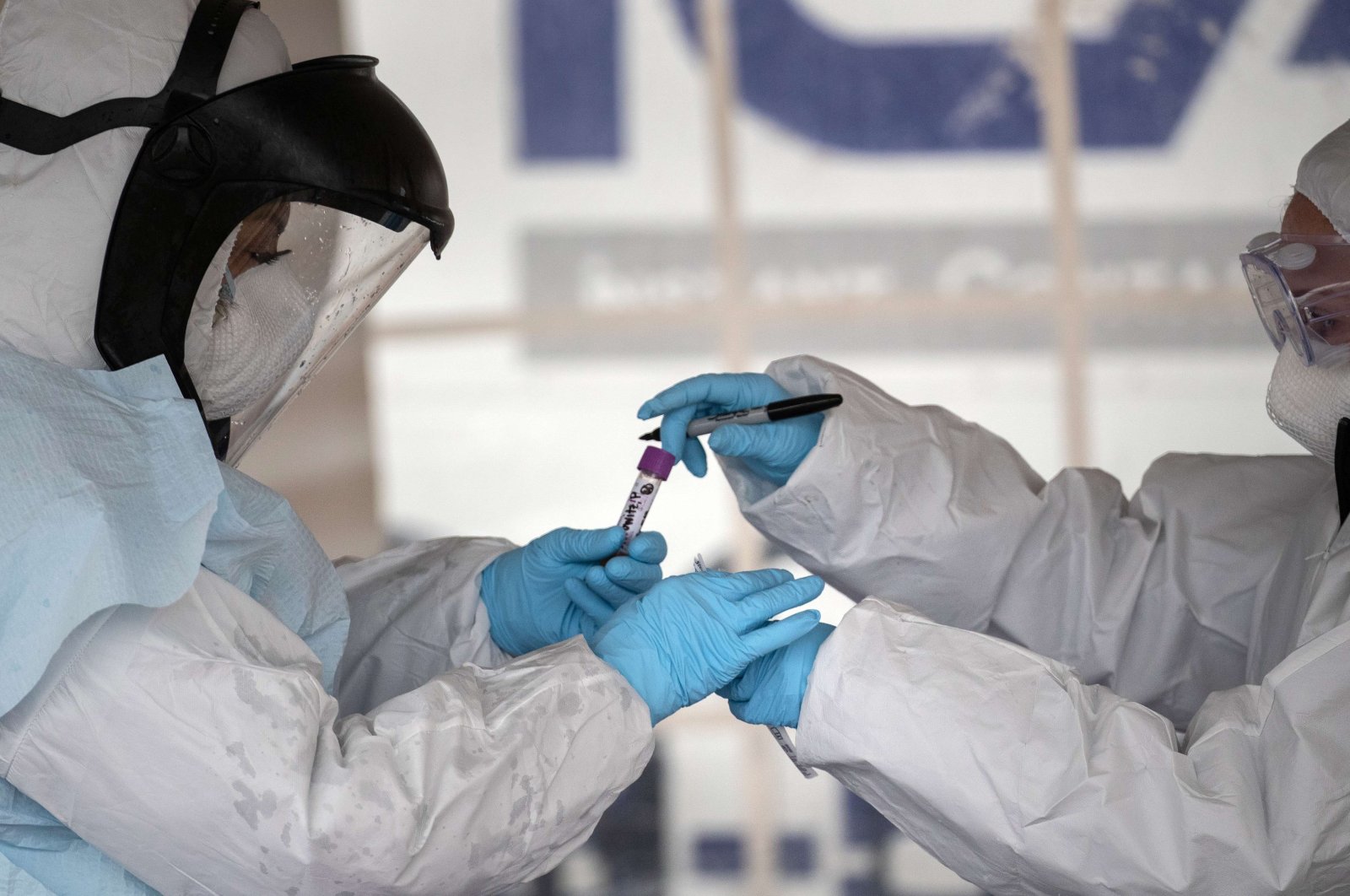 Health workers dressed in personal protective equipment (PPE) handle a coronavirus test at a drive-thru testing station at Cummings Park on March 23, 2020 in Stamford, Connecticut. (AFP Photo)