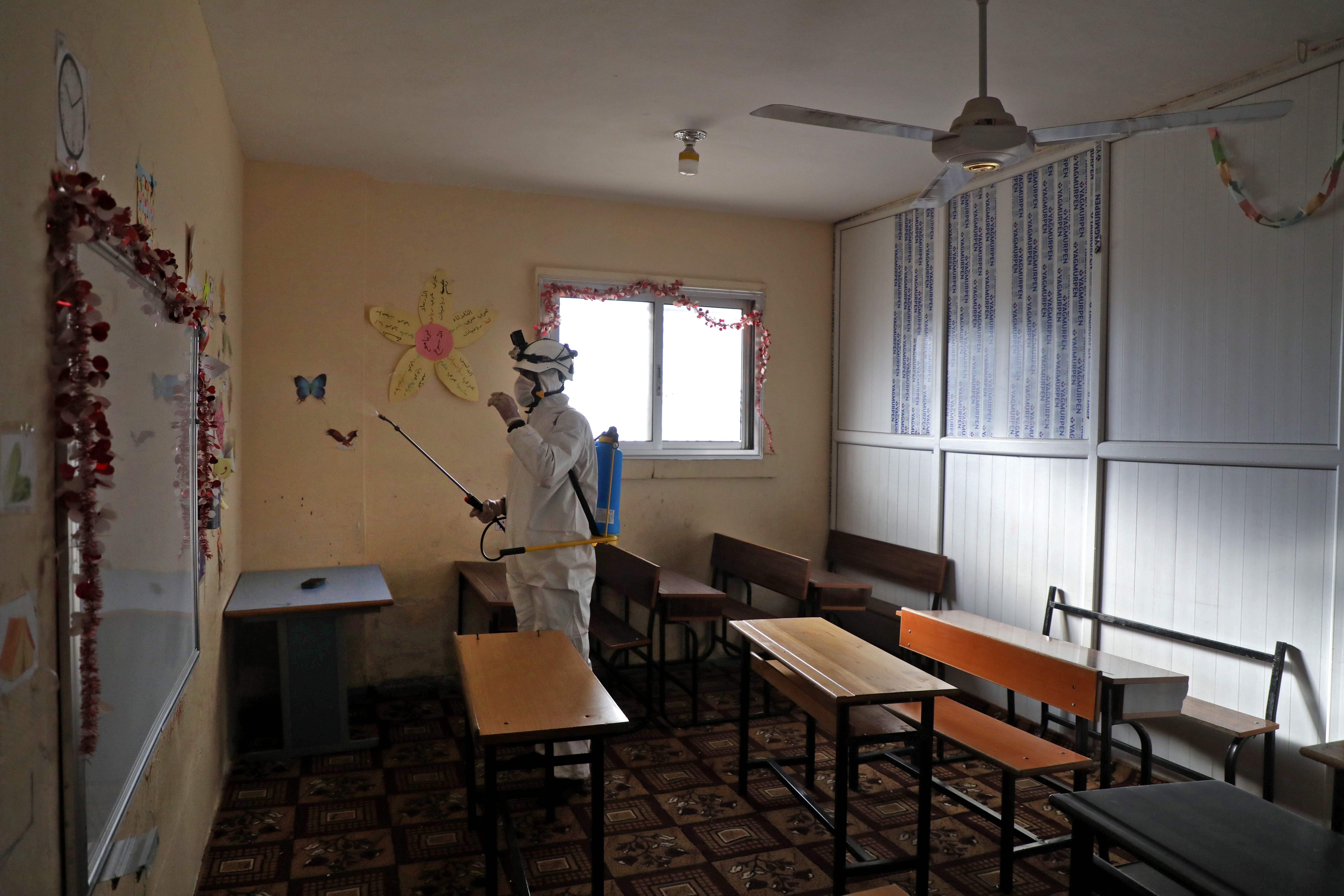 A member of the Syrian Civil Defence known as the 'White Helmets' disinfects a classroom, as part of preventive measures taken against infections by the novel coronavirus, in the Syrian town of Dana, east of the Turkish-Syrian border in the northwestern Idlib province,  Sunday, March 22, 2020.  (AFP)