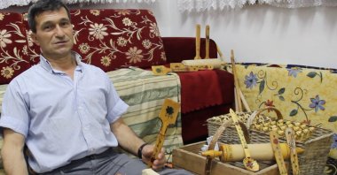 Lütfü Uğur poses with his wooden spoons, tablespoons, ladles and other products. (AA Photo)