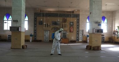 A member of the Syrian Civil Defence known as the "White Helmets" disinfects the interior of a mosque, as part of preventive measures taken against infections by the novel coronavirus, in the Syrian town of Dana, east of the Turkish-Syrian border in the northwestern Idlib province, Sunday, March 22, 2020.  (AFP)