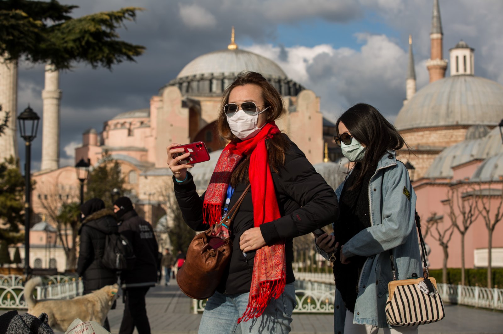 Tourists wearing protective face masks due to coronavirus concerns stroll in Sultanahmet Square in Istanbul, Turkey, Wednesday, March 18, 2020. The Byzantine-era monument of Hagia Sophia is seen in the background. (DHA Photo)