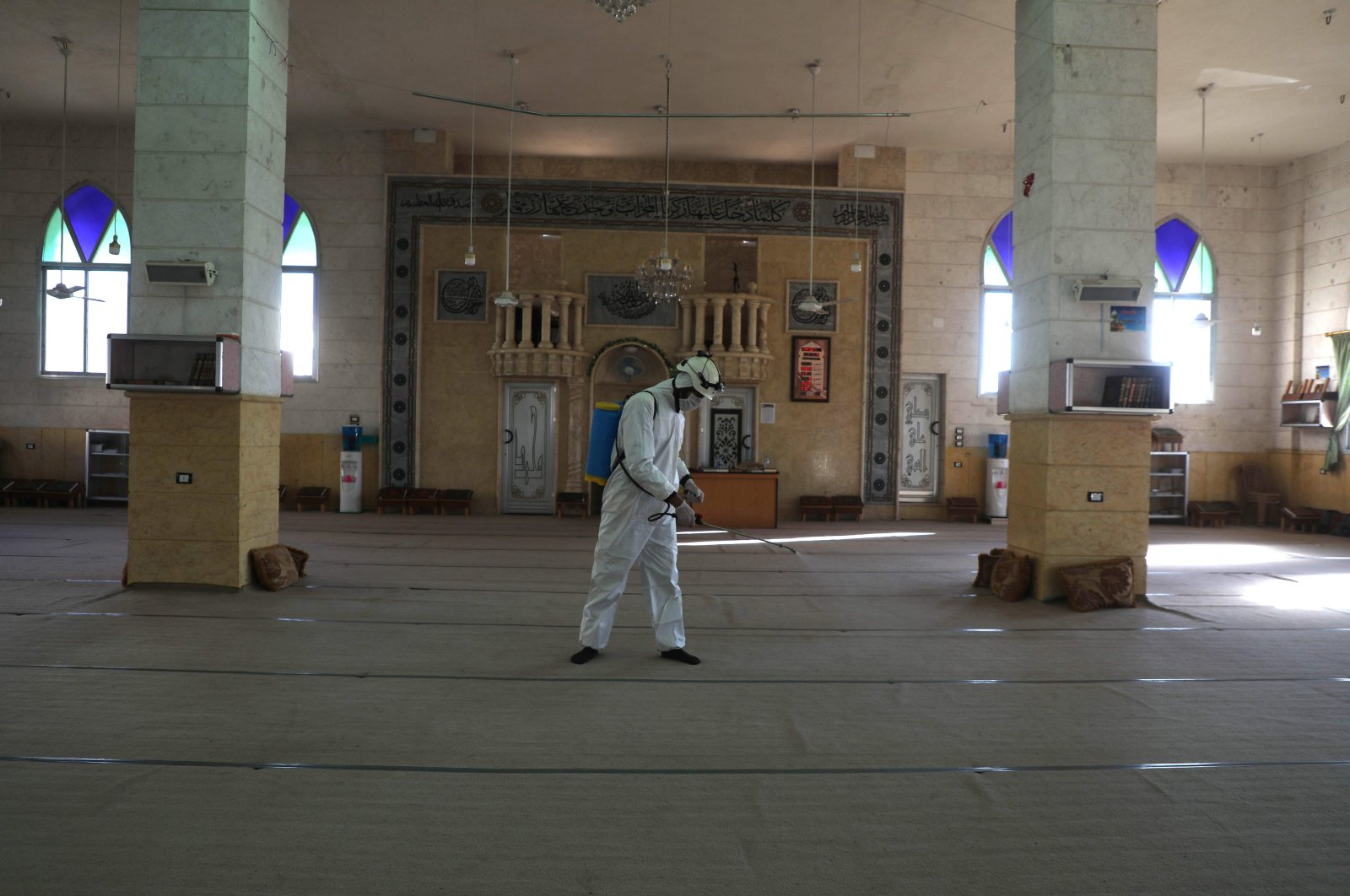 A member of the Syrian Civil Defence known as the "White Helmets" disinfects the interior of a mosque, as part of preventive measures taken against infections by the novel coronavirus, in the Syrian town of Dana, east of the Turkish-Syrian border in the northwestern Idlib province, Sunday, March 22, 2020.  (AFP)