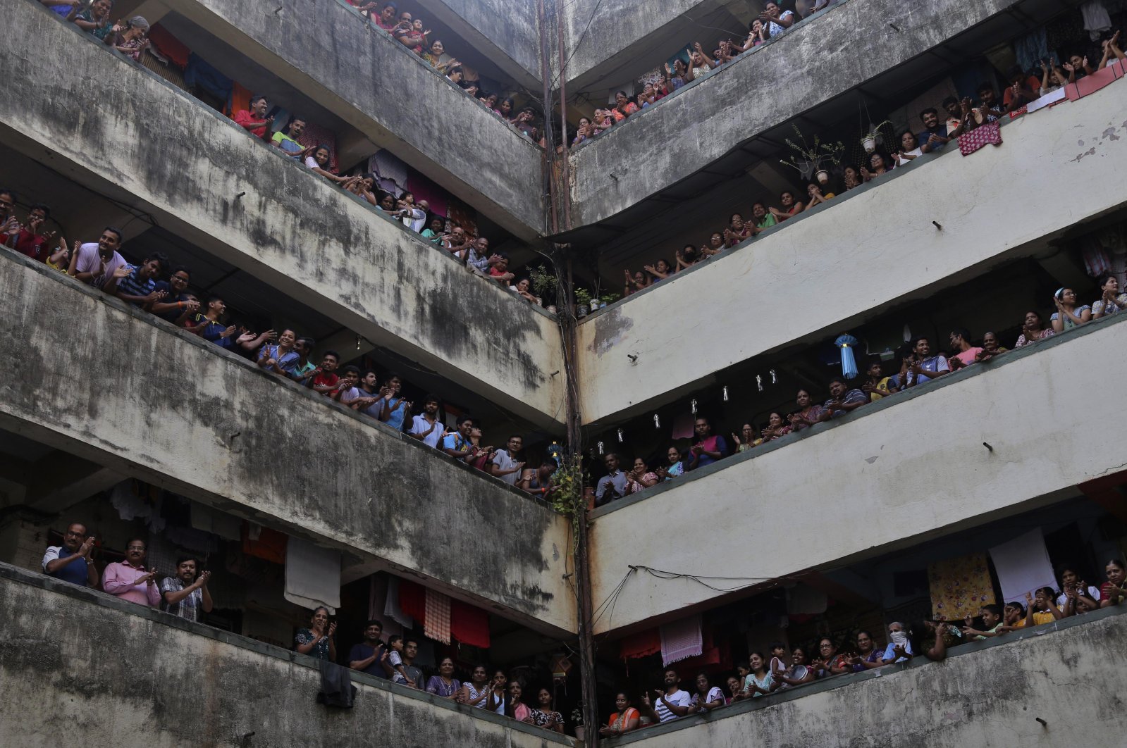 People clap from balconies in a show of appreciation for health care workers at a chawl, Mumbai, India, Sunday, March 22, 2020. (AP Photo)