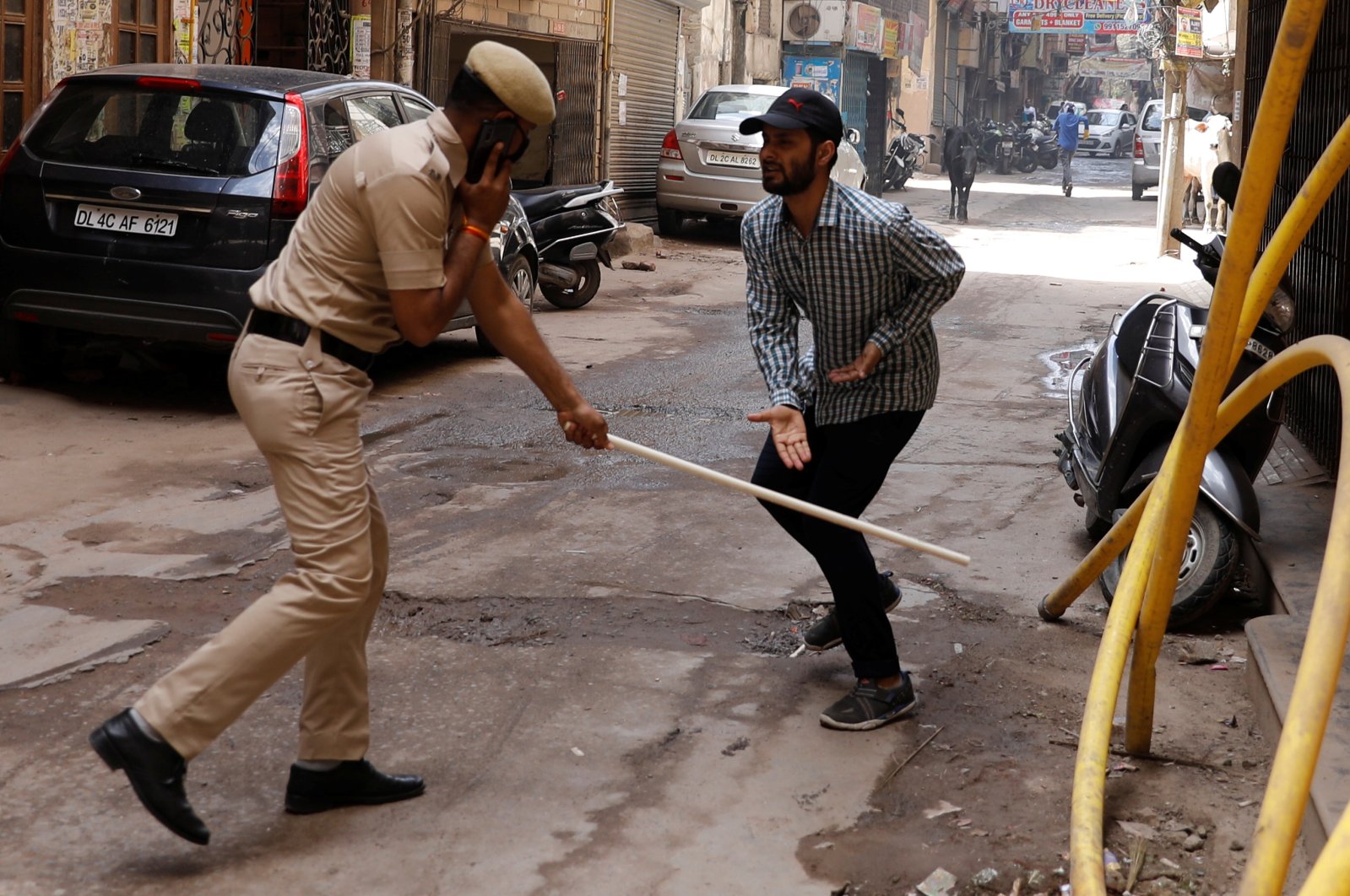 A police officer wields his baton against a man as a punishment for breaking the lockdown rules, New Delhi, Wednesday, March 25, 2020. (Reuters Photo)