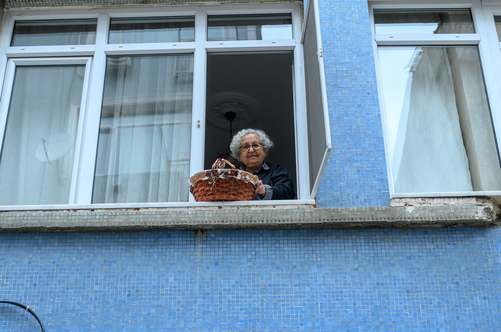 Lütfiye Yeşilbaş, an 89-year-old Turkish woman who lives alone in her home, lowers her basket in Kadıköy, Istanbul, Monday, March 23, 2020. (AFP Photo)