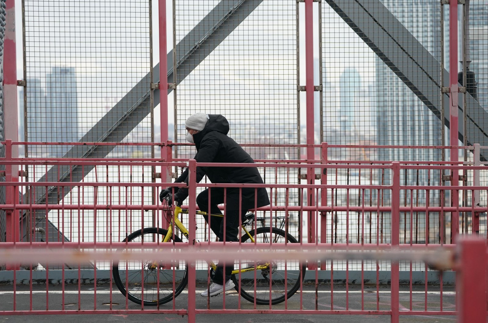 A cyclist wearing a mask rides over the Williamsburg Bridge in the Borough of Brooklyn on March 25, 2020 in New York. (AFP Photo)
