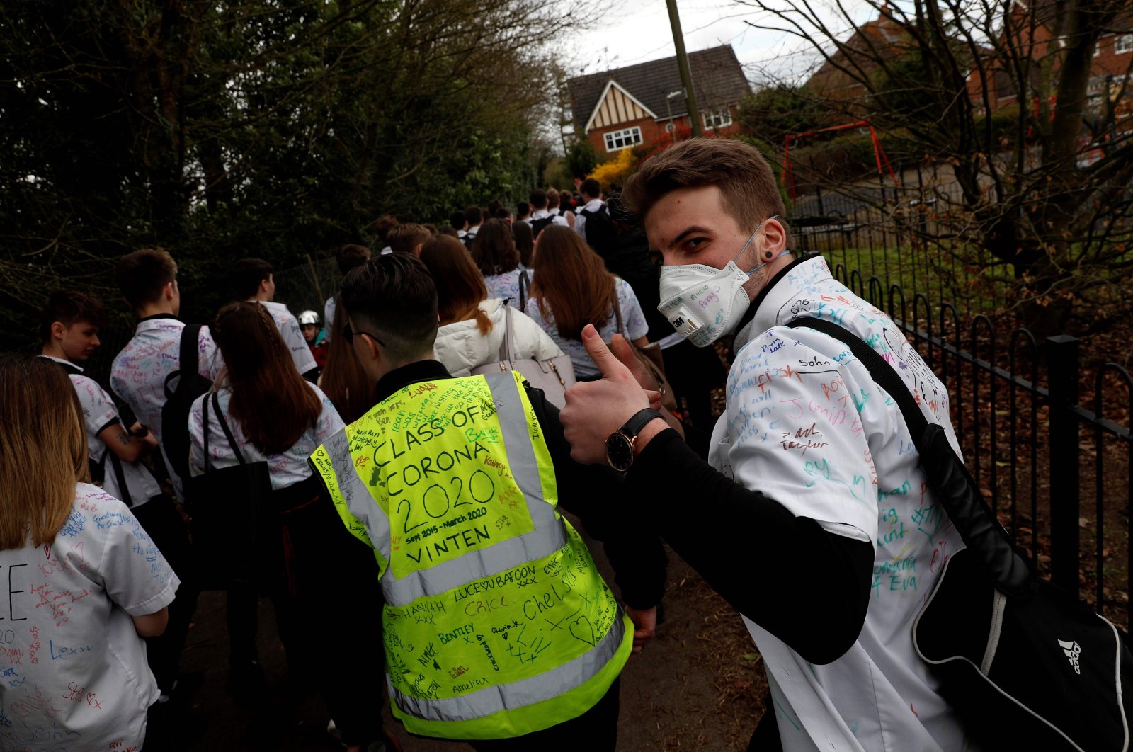 Year 11 pupils, some with graffiti-covered shirts reading 'Survivor 2020' and 'Class of Corona 2020' react as they leave a secondary school in Odiham, west of London on March 20, 2020.