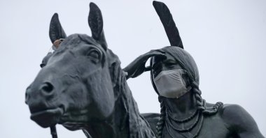 A statue of a Sioux Indian scout wears a face mask as it stands on a bluff overlooking Kansas City, Mo., Thursday, March 26, 2020. (AP Photo)