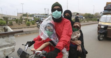 A family travels on a motorcycle wearing face masks during a government-imposed nationwide lockdown, as a preventive measure to contain the coronavirus, in Karachi, Pakistan, Thursday, March 26, 2020. (AP Photo)