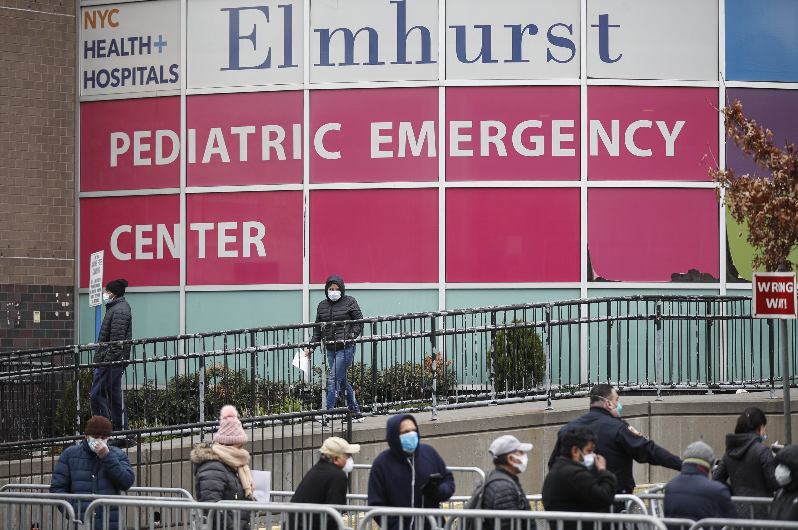 A woman exits a COVID-19 testing site while hundreds wait in line at Elmhurst Hospital Center, New York, Wednesday, March 25, 2020. (AP Photo)