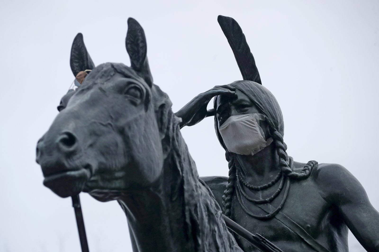 A statue of a Sioux Indian scout wears a face mask as it stands on a bluff overlooking Kansas City, Mo., Thursday, March 26, 2020. (AP Photo)