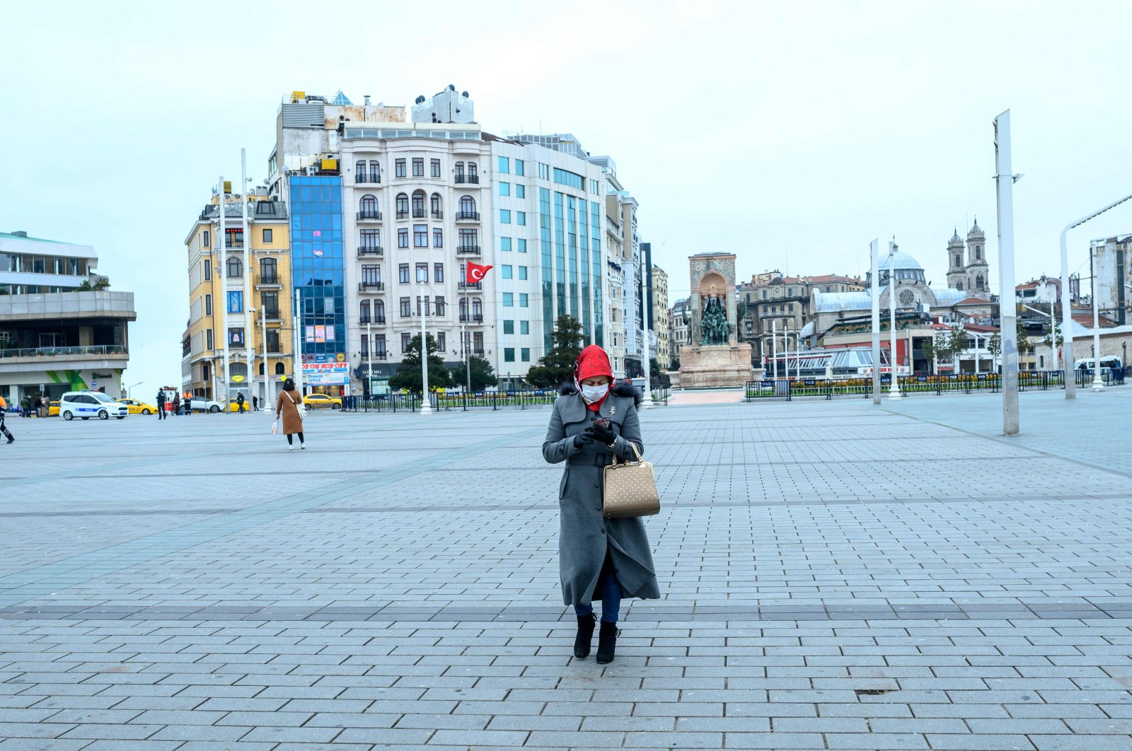 A woman wearing a mask walks across Taksim Square, Istanbul, Turkey, Thursday, March 26, 2020. (AFP Photo)