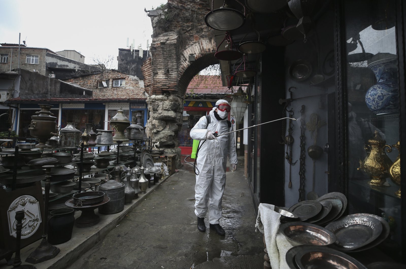 A municipality worker wearing a protective suit sprays disinfectant at the iconic Grand Bazaar in Istanbul, one of the city's main tourist attractions, that shut down amid the coronavirus outbreak, Wednesday, March 25, 2020. (AP Photo)