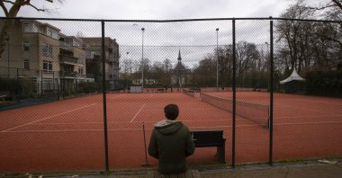A man talks on his mobile phone outside a closed tennis club in Amsterdam, Netherlands, Wednesday, March 18, 2020. (AP Photo)
