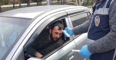 A police officer checks the temperature of a driver in Kırklareli, Turkey, Saturday, March 28, 2020. (İHA Photo)