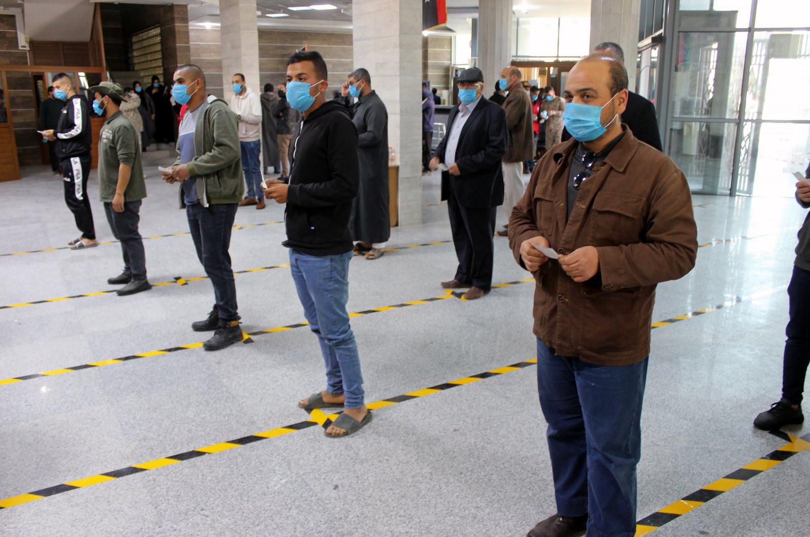 People wear protective masks, as part of precautionary measures against coronavirus disease (COVID-19), as they stand in a queue at a bank in Misrata, Libya March 22, 2020. Picture taken March 22, 2020. (Reuters Photo)