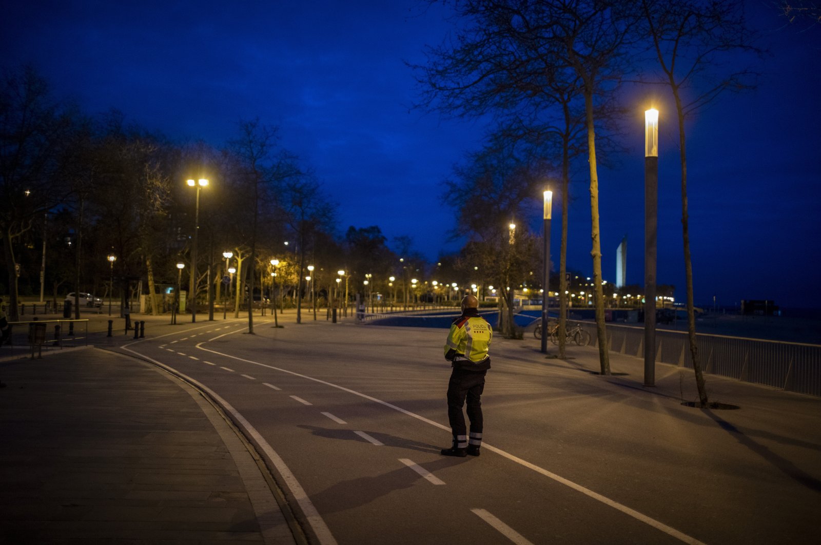 A Catalan police officer stands guard in an empty promenade in Barcelona, Spain, Saturday, March 28, 2020. (AP Photo)