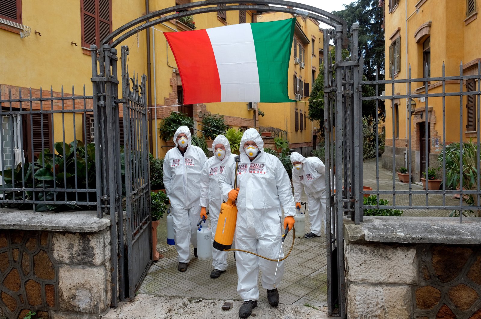 Workers wearing protective outfits sanitize a neighborhood to contain the spread of the coronavirus, Rome, Saturday, March 28, 2020. (AP Photo)