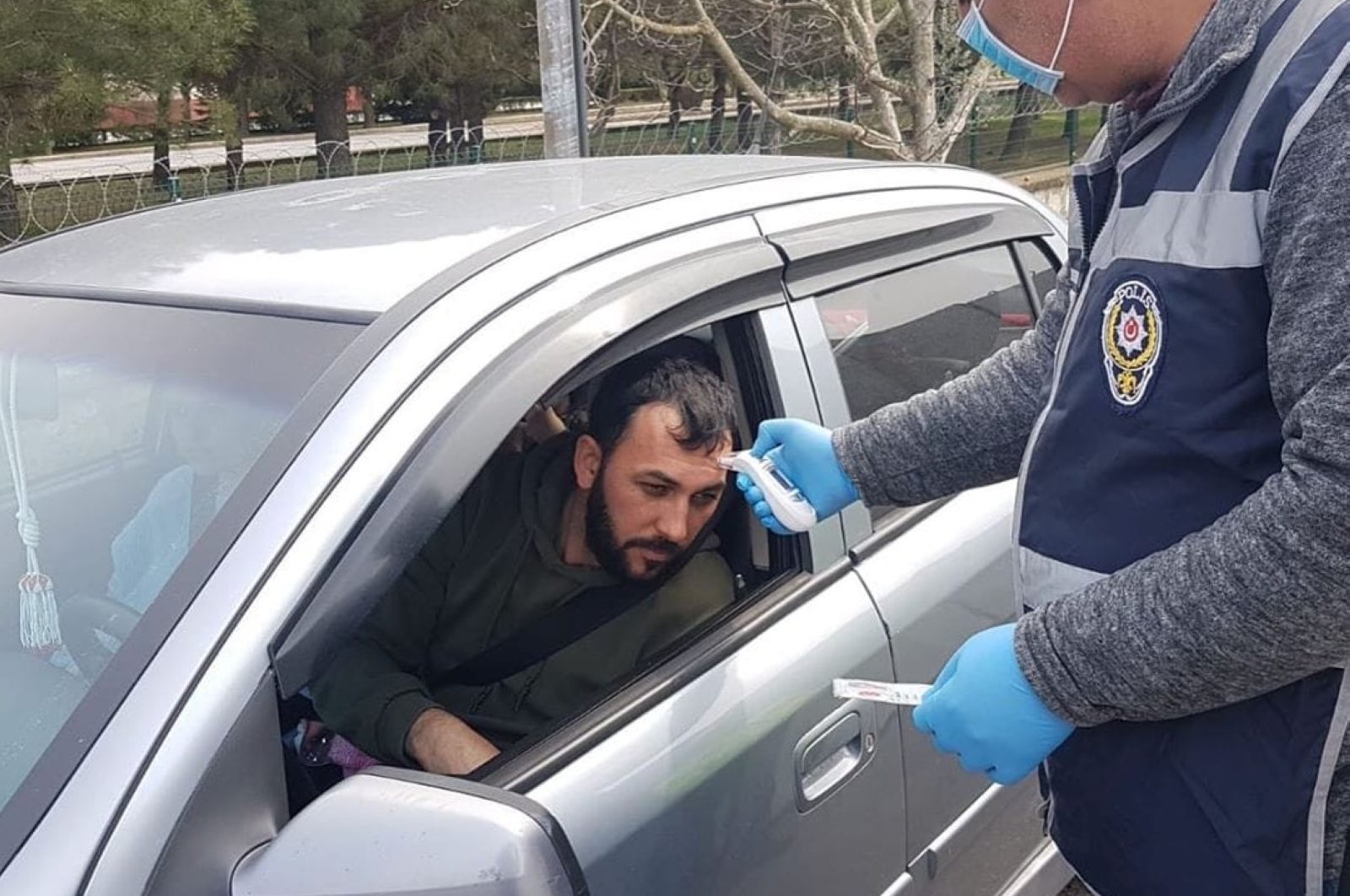 A police officer checks the temperature of a driver in Kırklareli, Turkey, Saturday, March 28, 2020. (İHA Photo)
