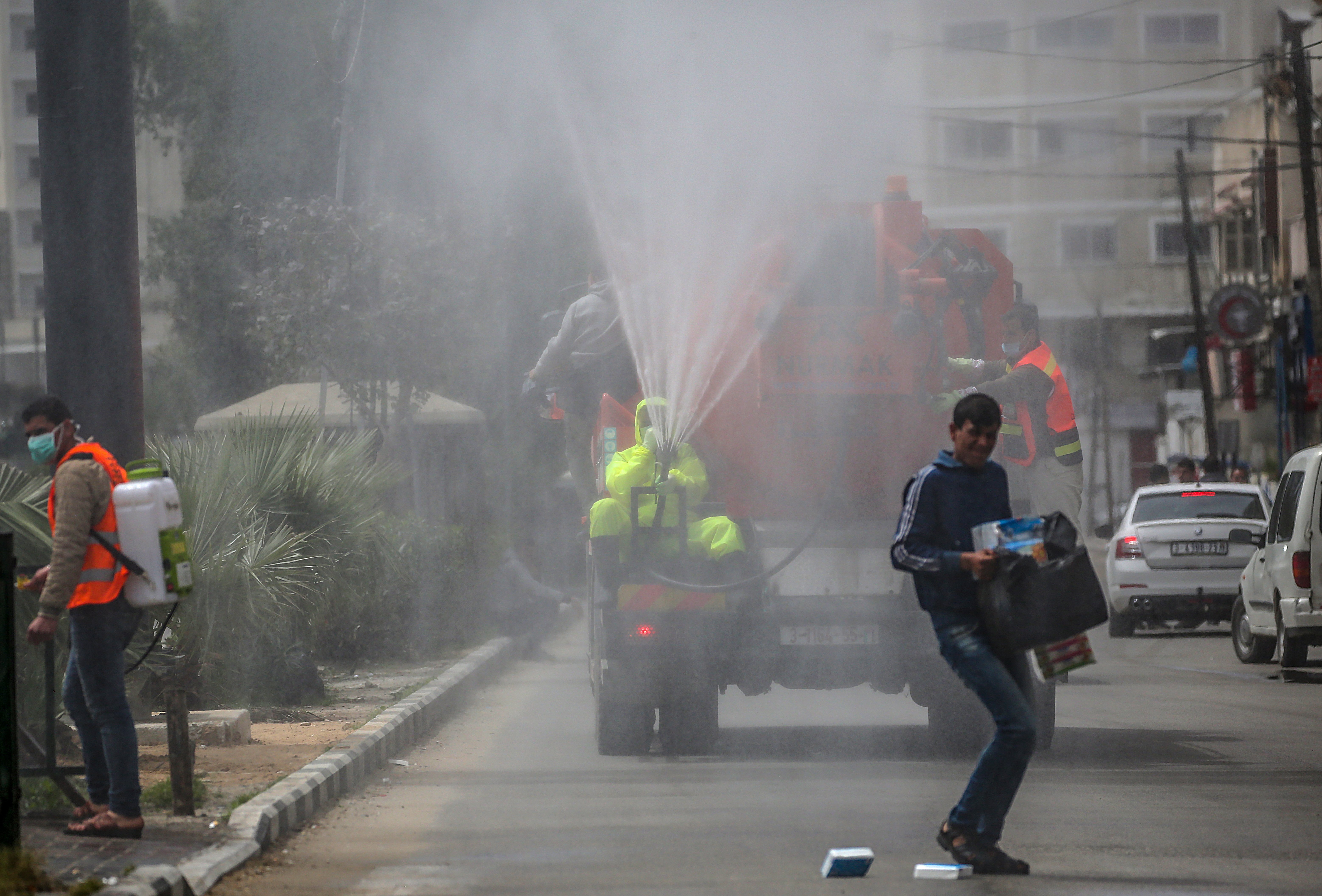 A Palestinian man sprays disinfectant as a precaution against the spread of the SARS-CoV-2 coronavirus which causes the COVID-19 disease, in the streets of Gaza City, Monday, March 30, 2020. (EPA Photo)