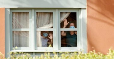 Guests, wearing protective face masks, look through a window at H10 Costa Adeje Palace, on the Spanish island of Tenerife on Wednesday, Feb. 26, 2020. (REUTERS Photo)