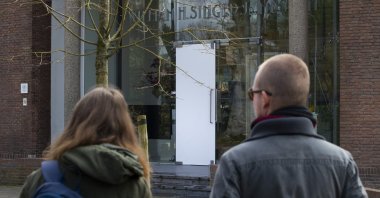 Two people look at the glass door which was smashed during a break-in at the Singer Museum in Laren, Netherlands, Monday March 30, 2020. (AP Photo)