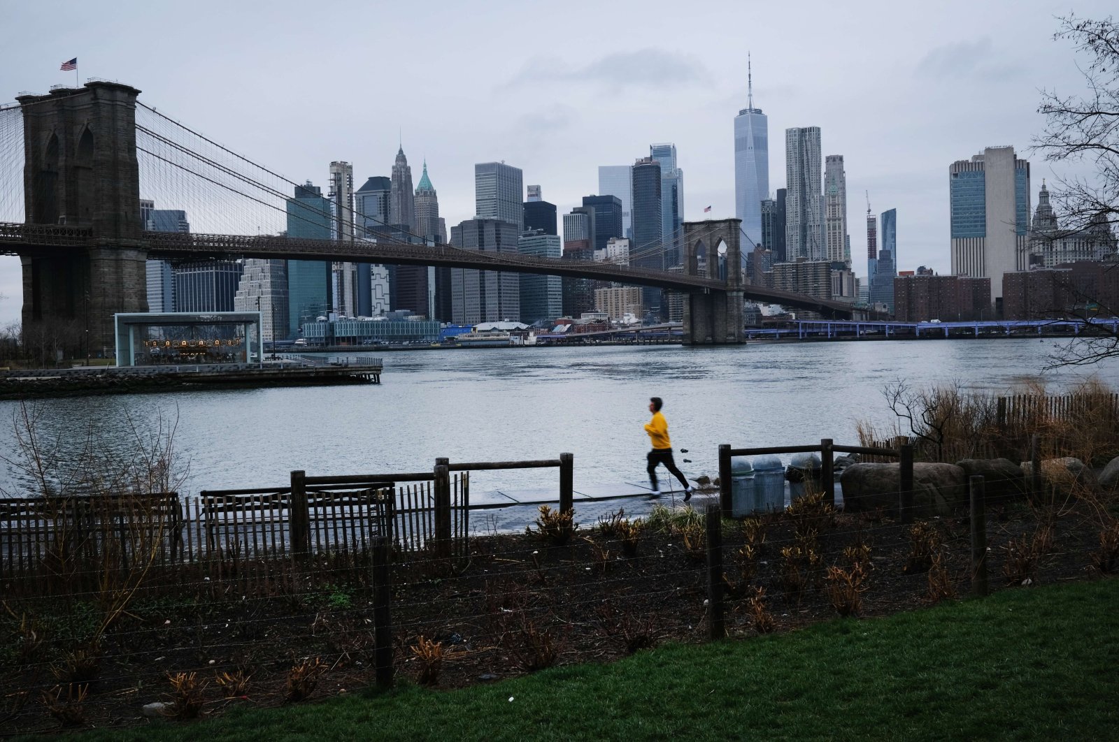A person runs in Brooklyn while lower Manhattan looms in the background, Saturday, March 28, 2020, in New York City, New York. (AFP Photo)