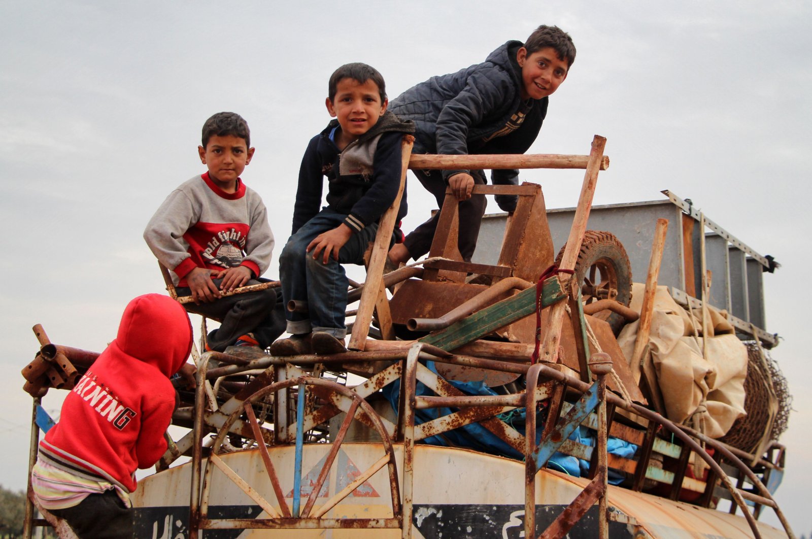 In this file photo taken on Feb. 15, 2020 children ride atop a water truck that is also loaded with furniture in the countryside of the village of Saharah, lying on the western edge of Syria's northern Aleppo province by Idlib province (AFP Photo)