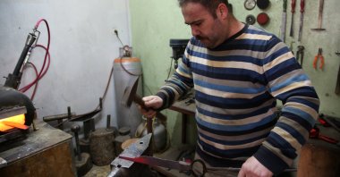 Fatih Altanay forges the iron he heats in a high-heat propane stove in his workshop. (AA Photo)