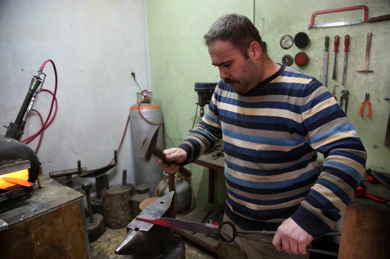 Fatih Altanay forges the iron he heats in a high-heat propane stove in his workshop. (AA Photo)