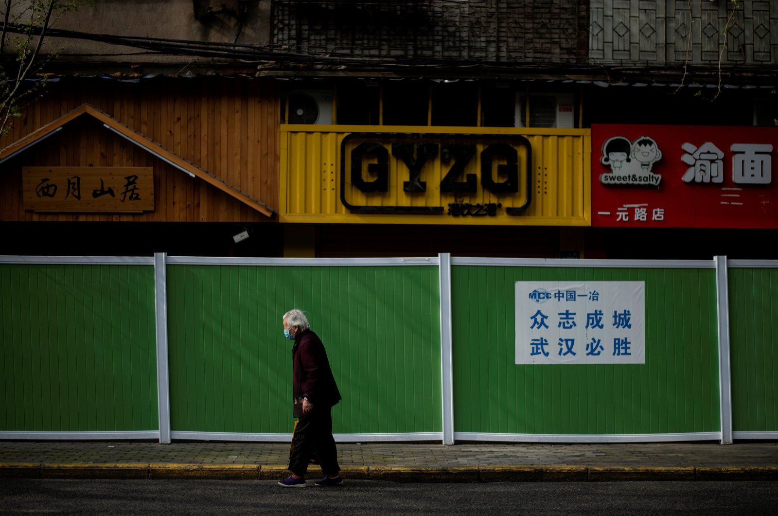 An elderly woman wearing a face mask walks along a street in Wuhan, in China's central Hubei province, Wednesday, April 1, 2020. (AFP Photo)