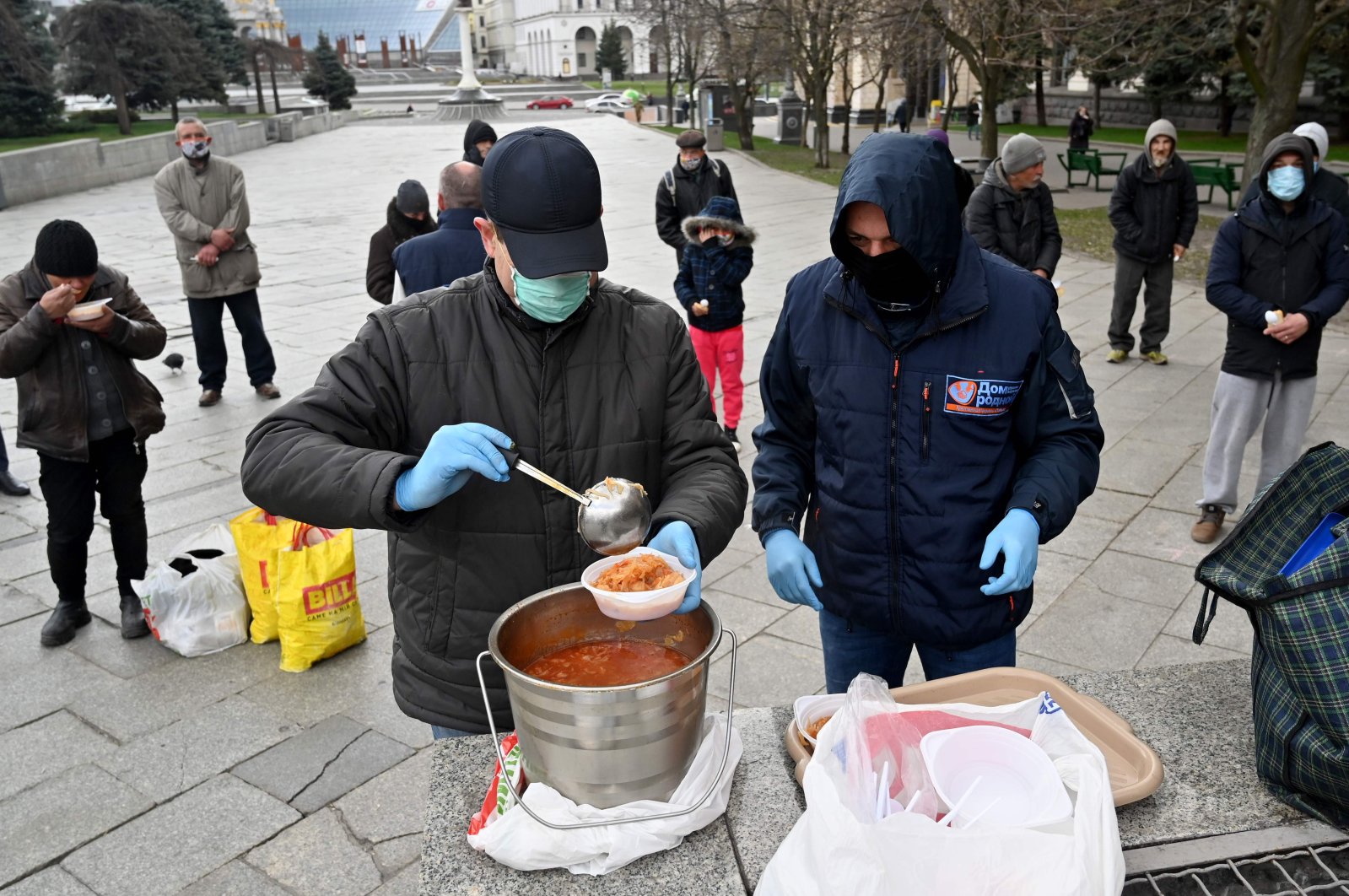 Homeless and vulnerable people some wearing face masks, amid concerns over the spread of the novel coronavirus, COVID-19, keep distance from each other as they queue to receive free meals being distributed by charity activists at Independence Square in the capital Kyiv on April 1, 2020. (AFP Photo)