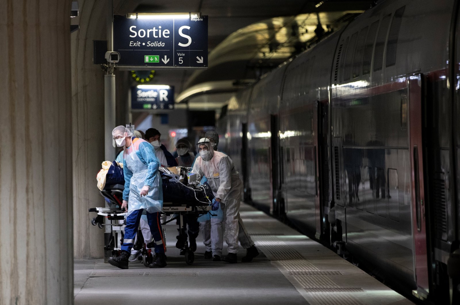 Medical staff carry a patient infected with the COVID-19 into a medicalised TGV high speed train at the Gare d'Austerlitz train station on April 1, 2020 in Paris, France (EPA Photo)