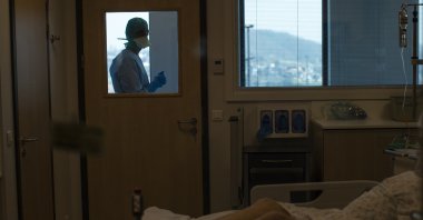 In this photograph taken from behind a window, medical personnel work in the intensive care ward for COVID-19 patients at the MontLegia CHC hospital in Liege, Belgium, Friday, March 27, 2020. (AP Photo)