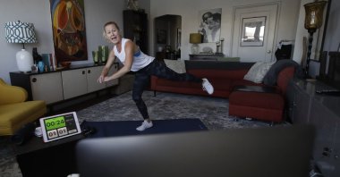 A woman shows how to perform a workout from her home in Oakland, California, U.S.,Thursday, March 26, 2020. (AP Photo)