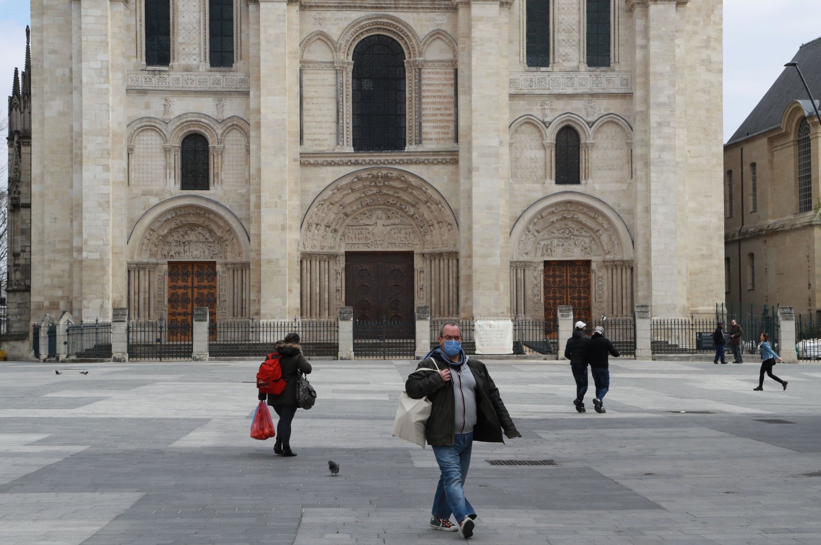 A man wearing a protective face mask walks in front of Saint-Denis Basilica on the seventeenth day of lockdown aimed at curbing the spread of COVID-19 in Saint-Denis, Paris on April 2, 2020. (AFP Photo)