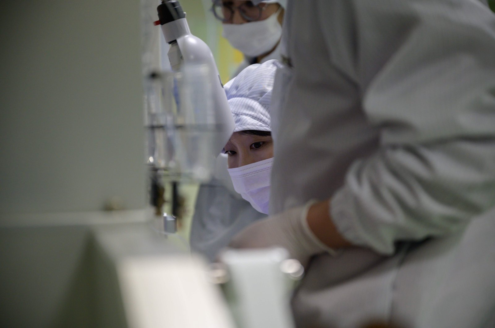 Staff members monitor a machine dispensing COVID-19 novel coronavirus antigen and antibody diagnostic material onto a membrane, on a production line making virus testing kits at the SD Biosensor bio-diagnostic company near Cheongju, south of Seoul on March 27, 2020. (AFP Photo)