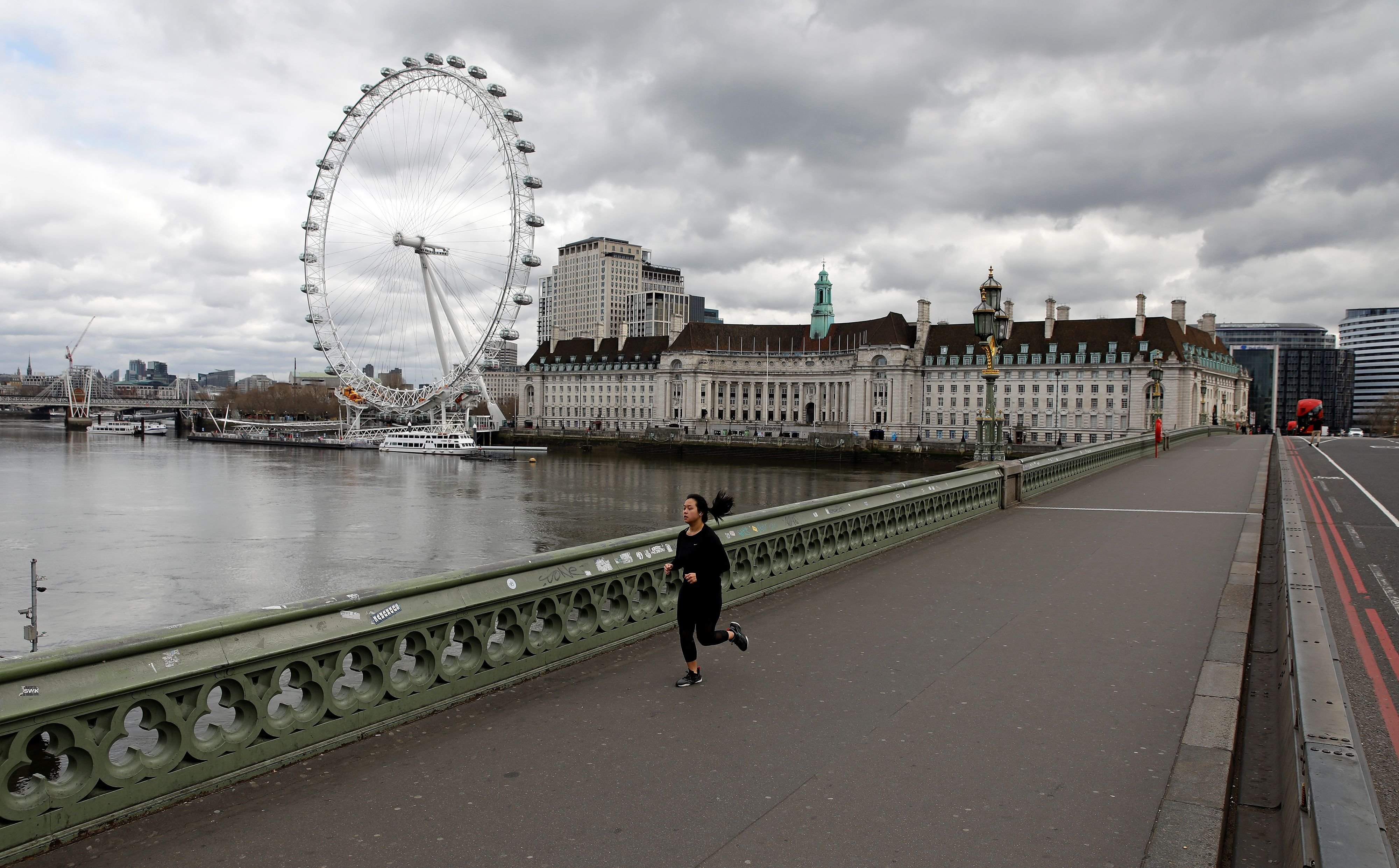 A woman wearing a face mask jogs across Westminster Bridge in London on Thursday, April 2, 2020, as life in Britain continues during the nationwide lockdown to combat the COVID-19 pandemic. (AFP Photo)
