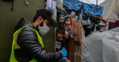 A member of nongovernmental organization "Team Humanity" shares handmade protective face masks with migrants and refugees in the camp of Moria on the island of Lesbos on Saturday, March 28, 2020 (AFP Photo)