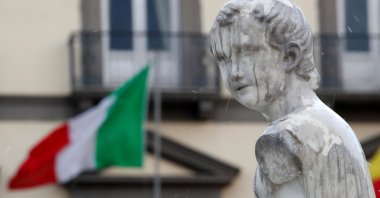 A statue on the Fountain of Neptune is seen in front of an Italian flag on Palm Sunday, following the coronavirus outbreak, in Naples, Italy, Sunday, April 5, 2020. (Reuters Photo)