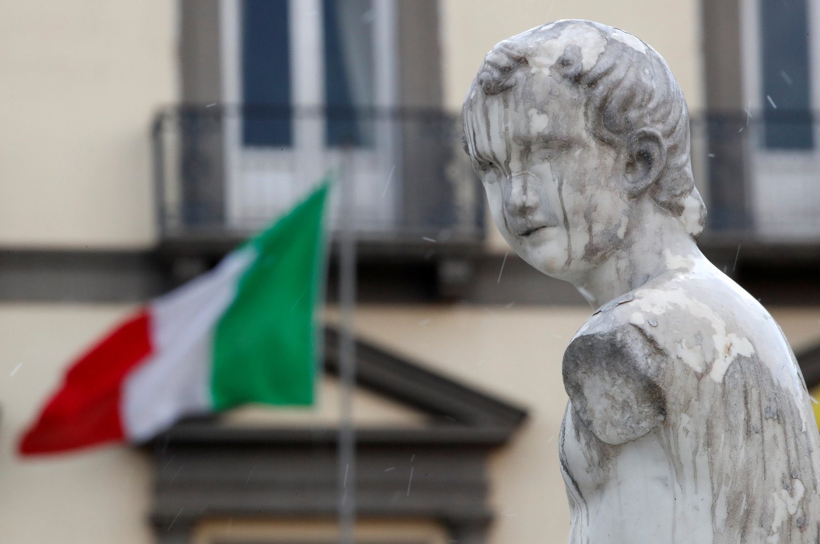 A statue on the Fountain of Neptune is seen in front of an Italian flag on Palm Sunday, following the coronavirus outbreak, in Naples, Italy, Sunday, April 5, 2020. (Reuters Photo)