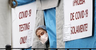 A medical worker sticks her head outside a COVID-19 testing tent set up outside Elmhurst Hospital Center in New York, Saturday, March 28, 2020. (AP Photo)
