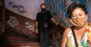 Maria Isabel Aguinaga, 72, wearing a protective face mask, descends the stairs of her crumbling residential building nicknamed “Luriganchito” after the country’s most populous prison, Lima, Peru, March 29, 2020. (AP Photo)
